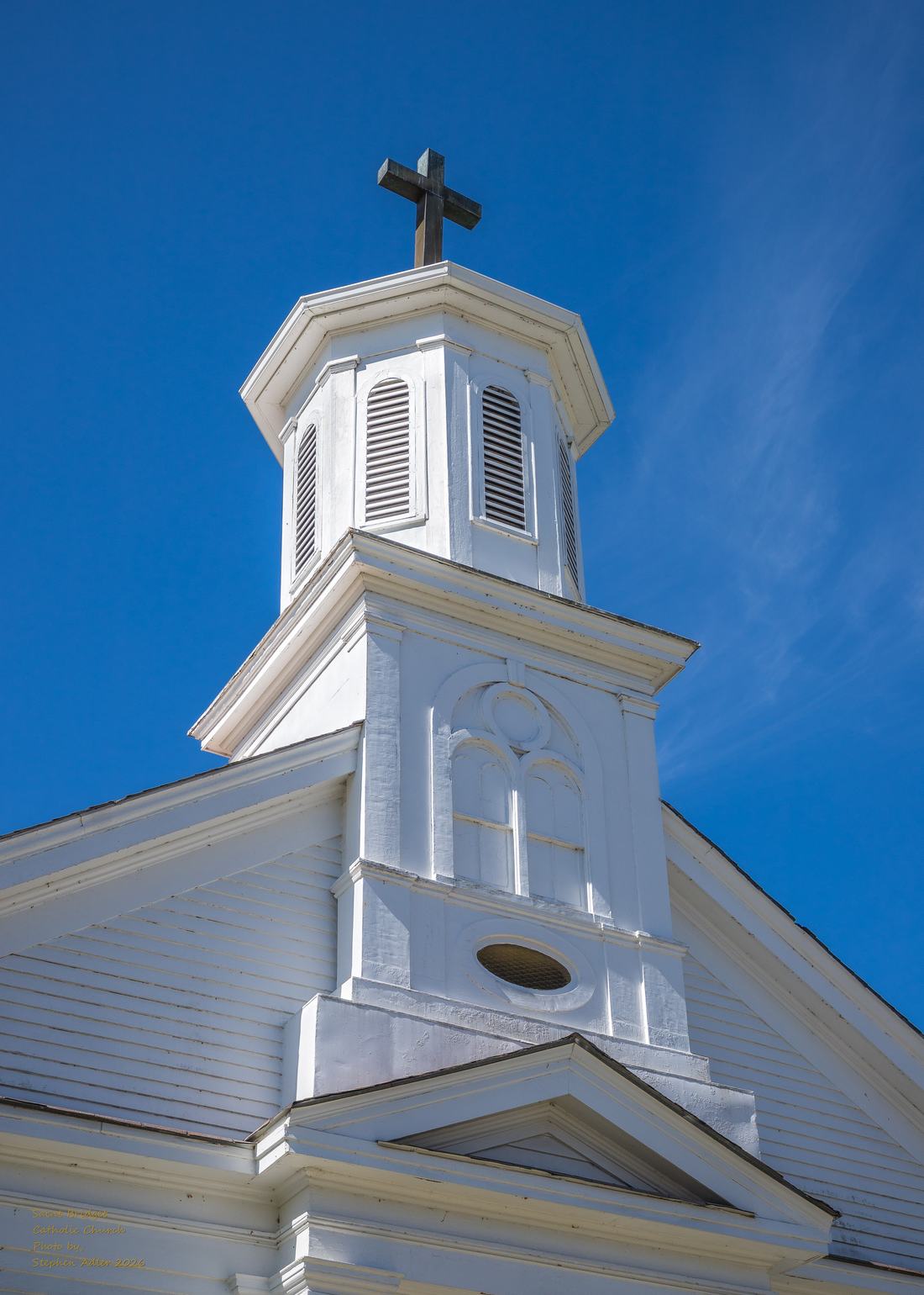The steeple of St. Bridget Catholic Church against a blue sky